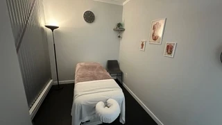 The Muscle IQ treatment room: massage table, lamp and framed prints